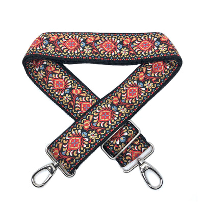 A close-up on white background of an adjustable length, woven bag strap with red, gold and black burst pattern and silver clasp.