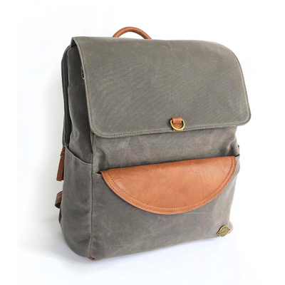 Large capacity grey canvas backpack with brown vegan leather accents and removable clutch. Three quarter view shows side pocket and separate zip-top laptop pocket on back of pack. 