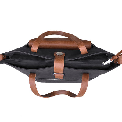 Top down view of black waxed canvas CarryAll Tote with caramel brown vegan leather accents, zipped on white background.