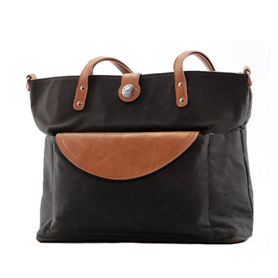 Black waxed canvas tote with brown vegan leather accents and brown clutch in front pocket, shown on white background.