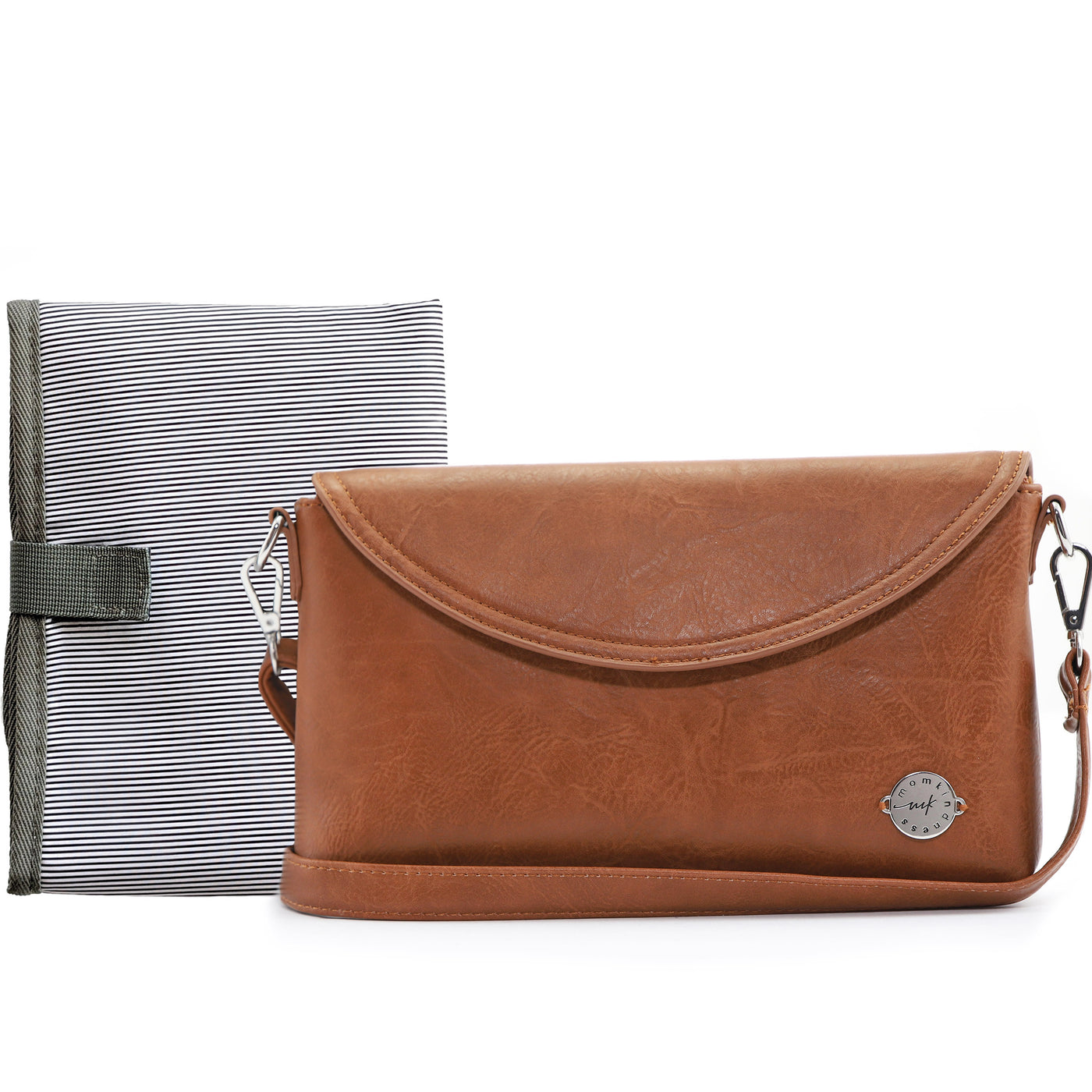 Caramel brown vegan leather clutch with crossbody strap on white tabletop, with folded B&W striped changing mat behind it. 