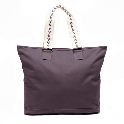 An extra-roomy canvas weekender tote in a graphite color with ivory embroidered shoulder straps with an arrow pattern, shown rear-facing on a white background.