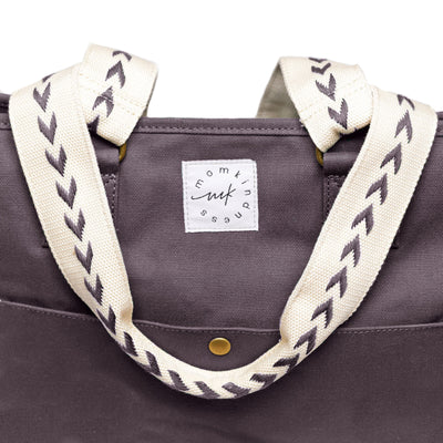 An extra-roomy canvas weekender tote in a graphite color with ivory embroidered shoulder straps with an arrow pattern, shown as a front-facing close-up on a white background.