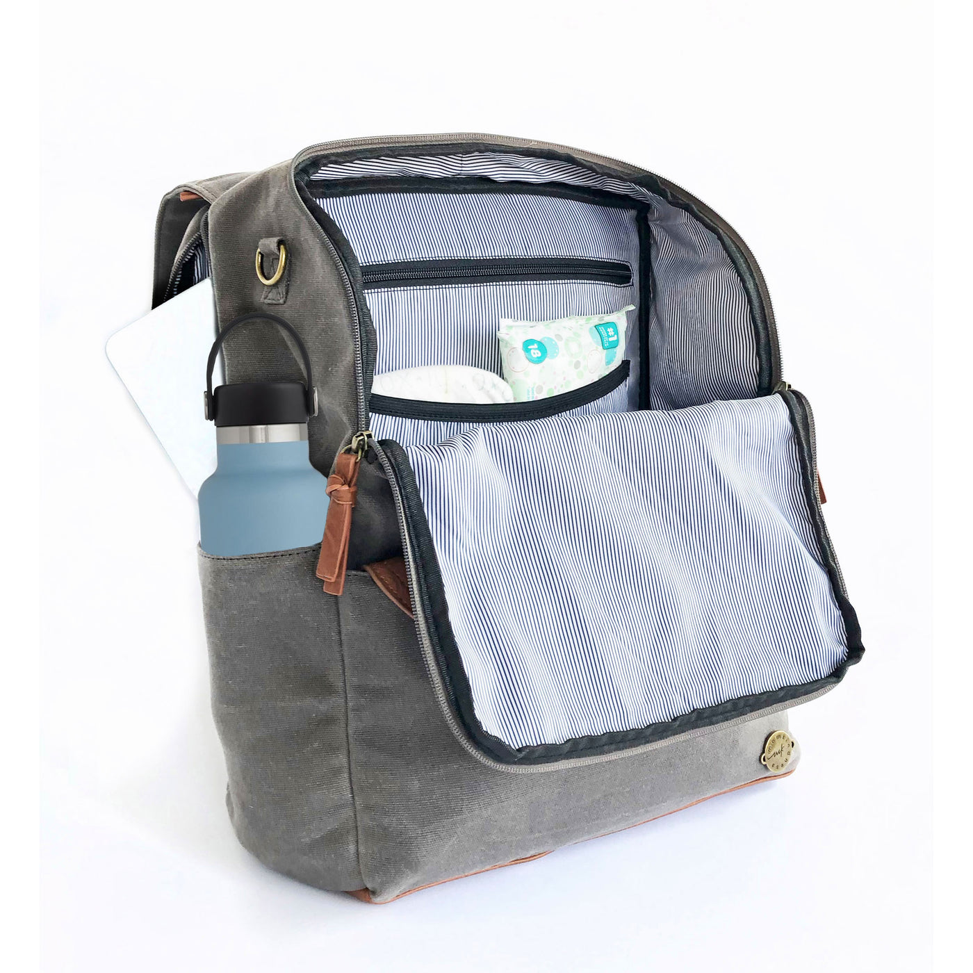 A front-facing 3/4 view of a grey canvas backpack with front flap zipped open showing pockets inside, a water bottle in side pocket, and a laptop in separate back compartment. Wipe-clean lining is a thin black and white stripe pattern with black accents. Image shown on a white background.