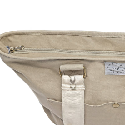 A close-up showing the zip-top closure of a large capacity tan-colored canvas tote.