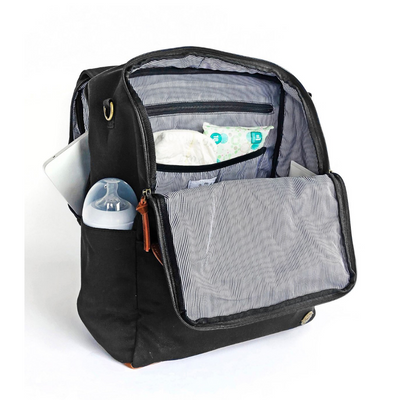 A front-facing 3/4 view of a black waxed canvas backpack diaper bag with front flap zipped open showing pockets inside, a baby bottle in side pocket, and a laptop in separate back compartment. Wipe-clean lining is a thin black and white stripe pattern with black accents. Image shown on a white background.