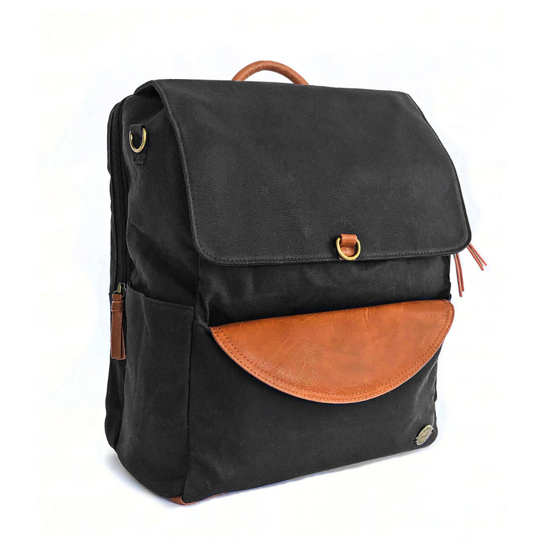Front-facing 3/4 view of large capacity black waxed canvas backpack with brown vegan leather accents and removable clutch. Side pocket and separate zip-top laptop pocket on back of pack can be seen as well as top carry handle. Image shown on white background.