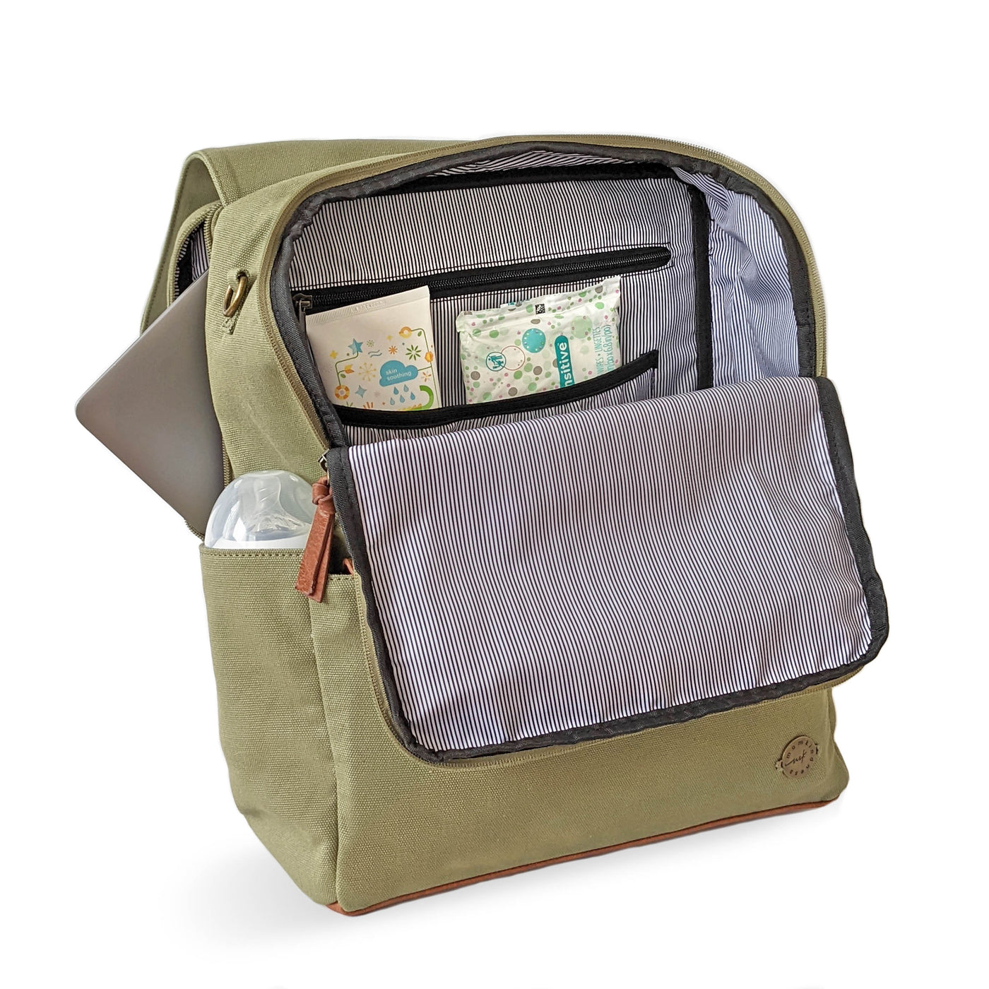 A laurel green colored canvas backpack diaper bag with caramel brown vegan leather accents, shown in 3/4 front view with the main compartment open to reveal interior pockets and striped lining, also with a baby bottle in side pocket.  